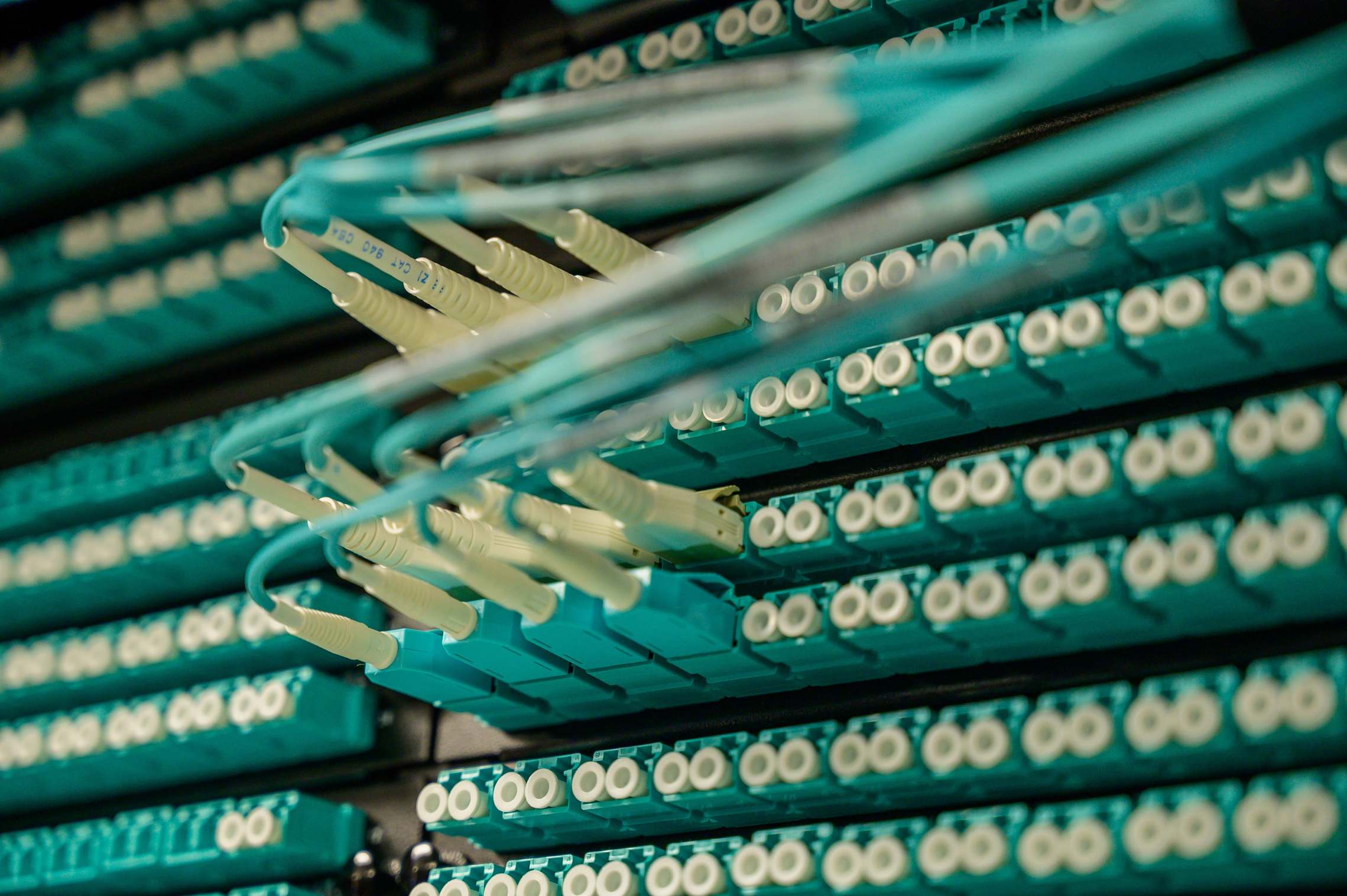 Server racks and network hardware in a data facility with fiber optic cables connected to a server rack